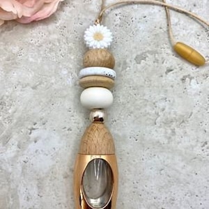 May include: A wooden car air freshener with a white daisy charm and a copper diffuser bottle. The beads are brown and white.