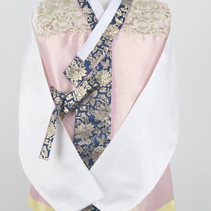 Może przedstawiać: Tradycyjny koreański hanbok, długa bluzka z różowym i białym gorsetem i białą spódnicą. Hanbok ma niebieską i złotą wzorzystą wstążkę zawiązaną w talii.