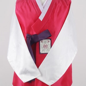 Może przedstawiać: Tradycyjny koreański hanbok, formalny strój, z różową górą, białymi rękawami i fioletowym pasem. Góra ma biały kołnierz i kwiatowy wzór z przodu.