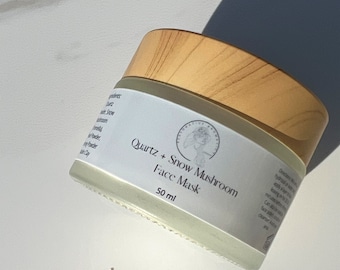 May include: A white jar with a wooden lid containing a light beige face mask powder. The jar is labeled "Quartz + Snow Mushroom Face Mask 50 ml".