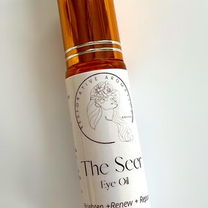 May include: A small, amber-colored glass bottle with a rollerball applicator. The bottle is labeled "The Seer Eye Oil" and "Brighten + Renew + Repair". The bottle contains 10 ml of product.