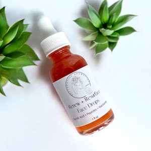 Może przedstawiać: Przezroczysta szklana butelka z białą etykietą i kroplomierzem. Etykieta zawiera napis "Renew + Resurface Face Drops Glycolic Acid + Peptides + Niacinamide 1 fl oz".