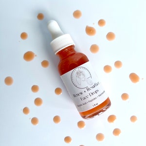 Może przedstawiać: Przezroczysta butelka szklana z białą pipetą wypełniona cieczą w kolorze brzoskwiniowym. Butelka jest oznaczona etykietą "Renew + Resurface Face Drops Glycolic Acid + Peptides + Niacinamide 1 fl oz".