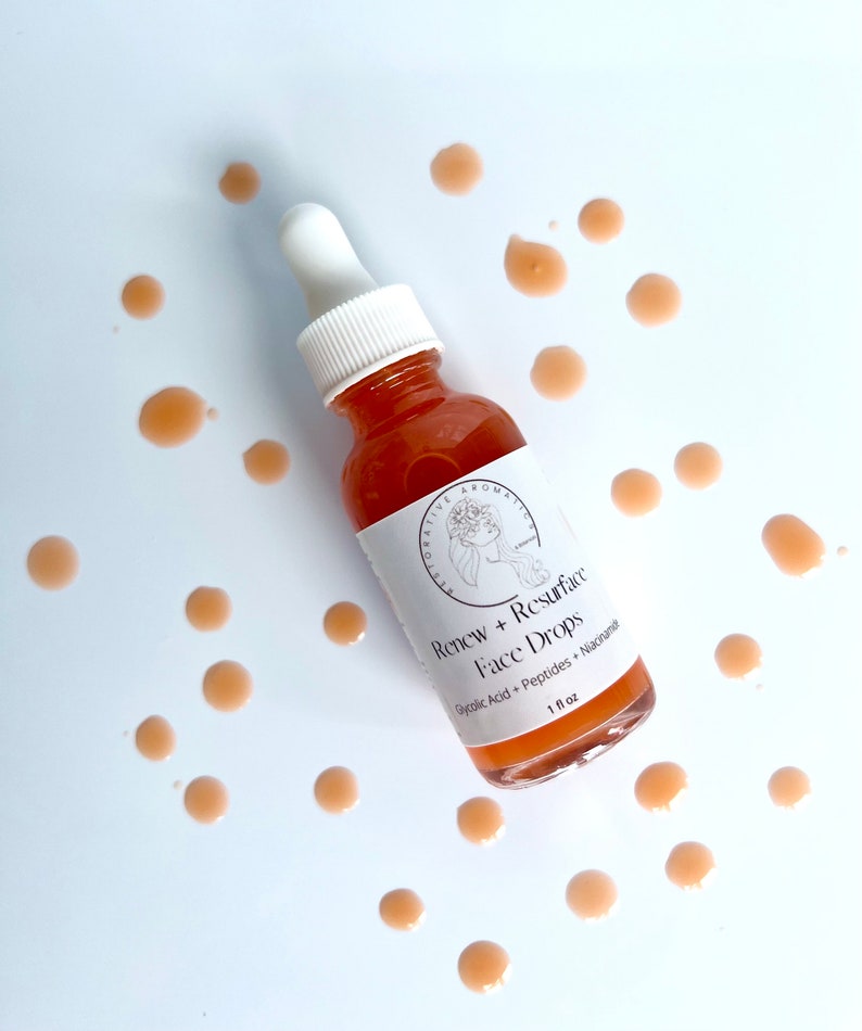 Może przedstawiać: Przezroczysta butelka szklana z białą pipetą wypełniona cieczą w kolorze brzoskwiniowym. Butelka jest oznaczona etykietą "Renew + Resurface Face Drops Glycolic Acid + Peptides + Niacinamide 1 fl oz".