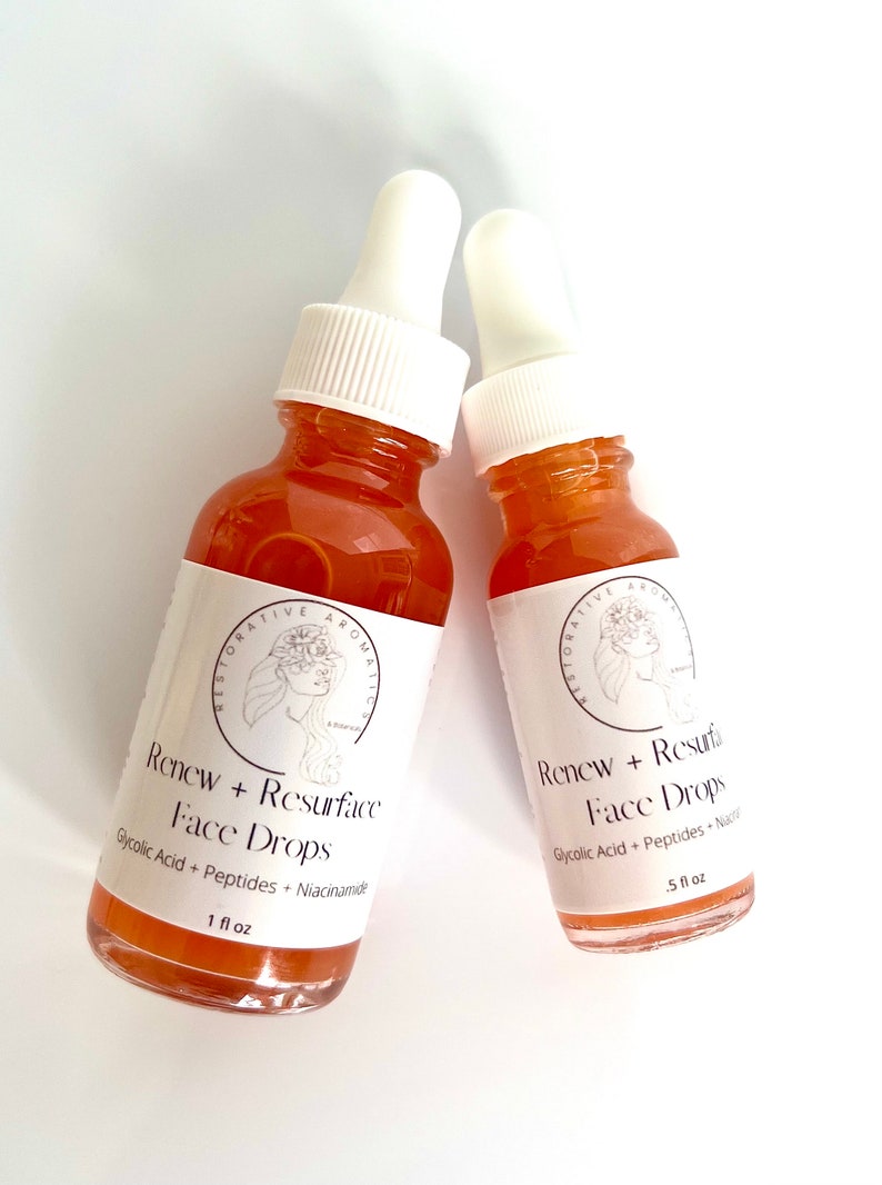 Może przedstawiać: Dwie bursztynowe butelki ze szklanymi kroplomierzami, oznaczone "Renew + Resurface Face Drops" i "Renew + Resurfa Face Drops". Butelki zawierają przezroczysty pomarańczowy płyn i są oznaczone składnikami "Glycolic Acid + Peptides + Niacinamide" i "Glycolic Acid + Peptides + Niacinamide". Butelki mają pojemność 1 fl oz i 5 fl oz.