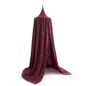 May include: A burgundy canopy bed tent with a conical top and flowing fabric. The fabric is adorned with small, scattered white star-like patterns. The tent is suspended from a single point, creating a draped effect.