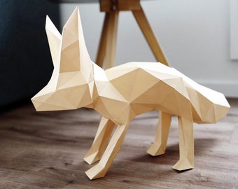 Puede incluir: Una escultura de papel de zorro beige con un diseño geométrico. El zorro está de pie sobre un suelo de madera.