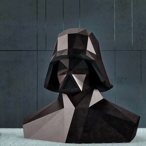 Puede incluir: Un busto geom&eacute;trico de Darth Vader en tonos de negro y gris. La escultura tiene un dise&ntilde;o poligonal, con &aacute;ngulos agudos y facetas. El busto se encuentra sobre un fondo gris oscuro.