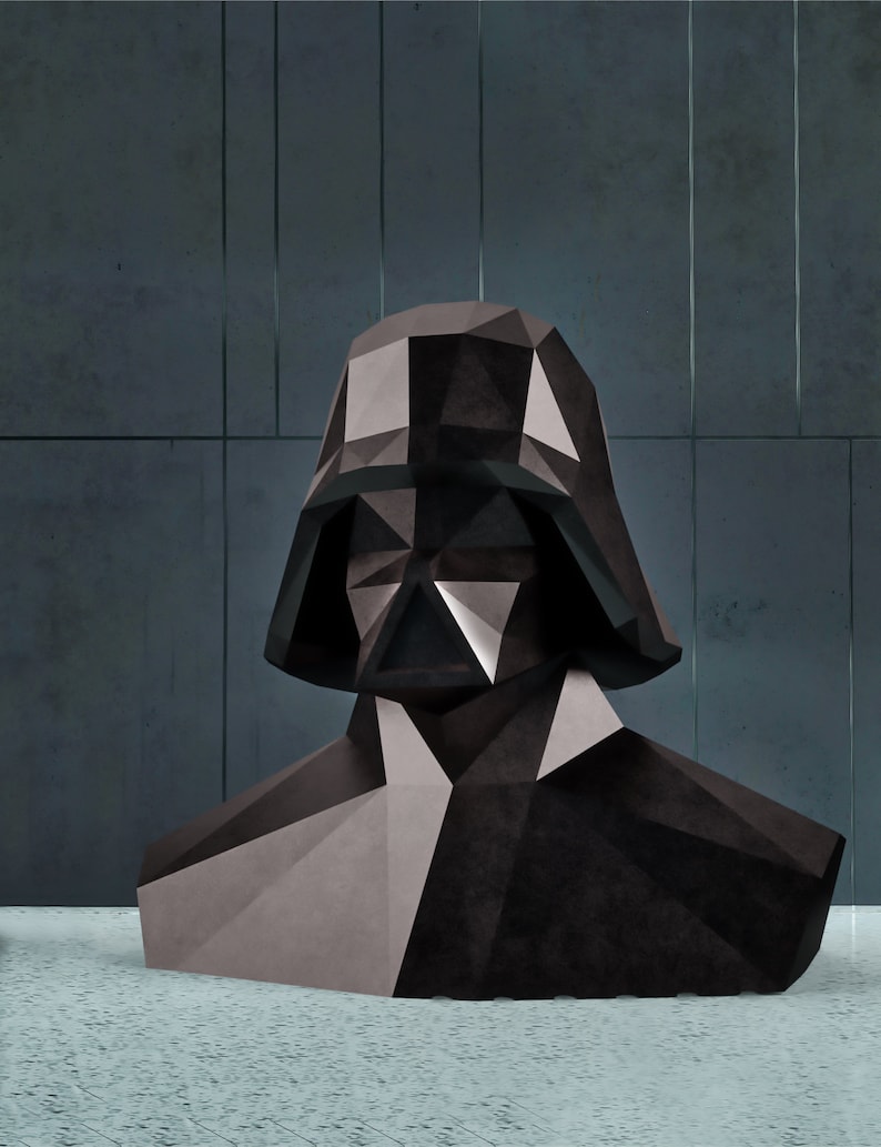 Puede incluir: Un busto geom&eacute;trico de Darth Vader en tonos de negro y gris. La escultura tiene un dise&ntilde;o poligonal, con &aacute;ngulos agudos y facetas. El busto se encuentra sobre un fondo gris oscuro.