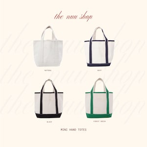May include: Four mini hand totes in a variety of colors. The totes are white with accents in natural, navy, black, and forest green. Each tote has a small pocket on the front and a handle at the top. The text "the nuu shop" is at the top.