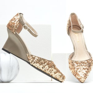 May include: A pair of gold sequined wedge heels with ankle straps. The heels are a light beige color and have a pointed toe.