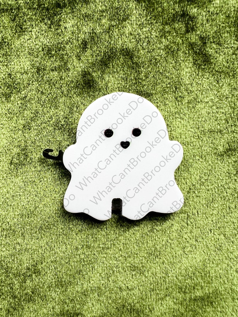 May include: White ghost-shaped ornament with black eyes and a heart-shaped mouth. The ornament has the text "What Can't Brooke Do" written on it.