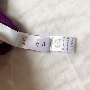 May include: A white clothing care label with black text. The label has the following information: IT, FR, DE, 2, 85, B, 75, 40&deg;C, NON CANDEGGIARE, ASCIUGARE ORIZZONTALE, NON STIRARE, NON LAVARE A SECCO, HAND WASH MAX 40&deg;C, DO NOT BLEACH.