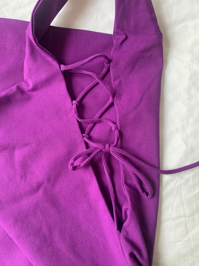 May include: Purple halter top with a lace-up back detail. The top is made of a soft, stretchy fabric.