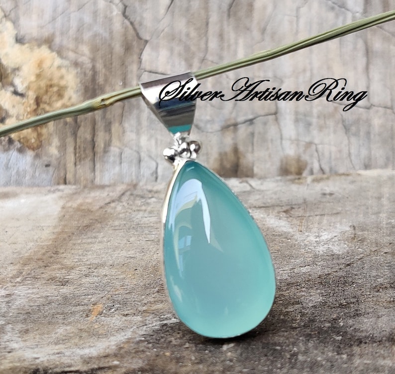 May include: A teardrop-shaped pendant with a light blue chalcedony stone set in sterling silver.
