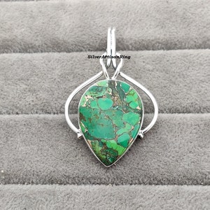 May include: A silver pendant featuring a green and brown gemstone in a teardrop shape. The pendant is set in a silver bail with a loop for attaching a chain.