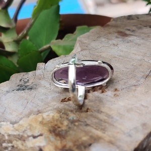 May include: A silver ring with a large oval amethyst gemstone. The ring is set in a simple band and the stone is faceted.