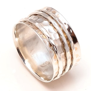 May include: A silver spinning ring with a hammered texture and three bands. The ring is marked with "925" on the inside.