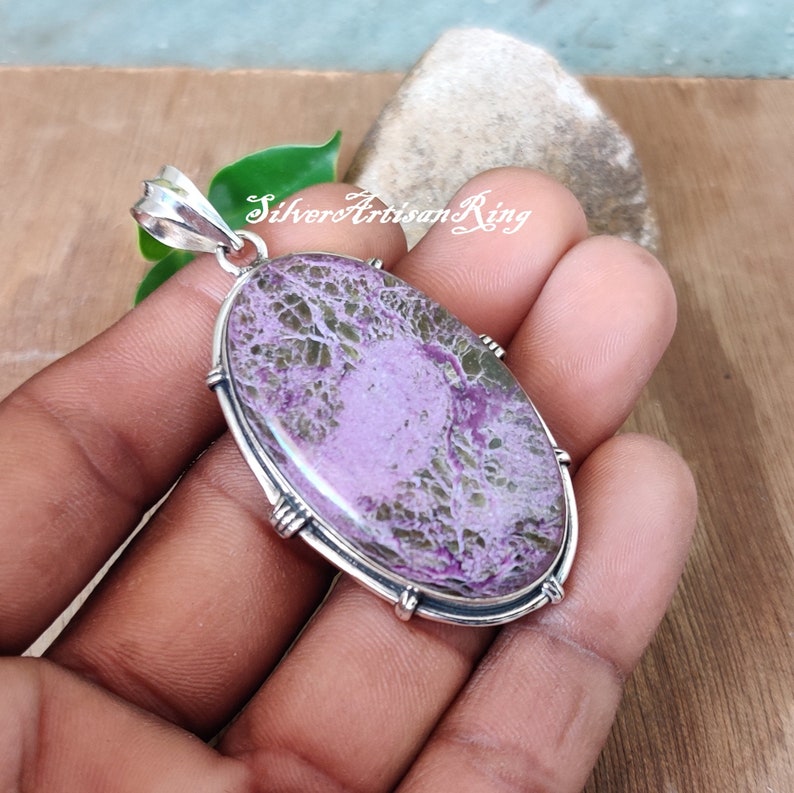 May include: A silver pendant with a purple and green stone set in a silver bezel. The stone has a unique, marbled pattern.