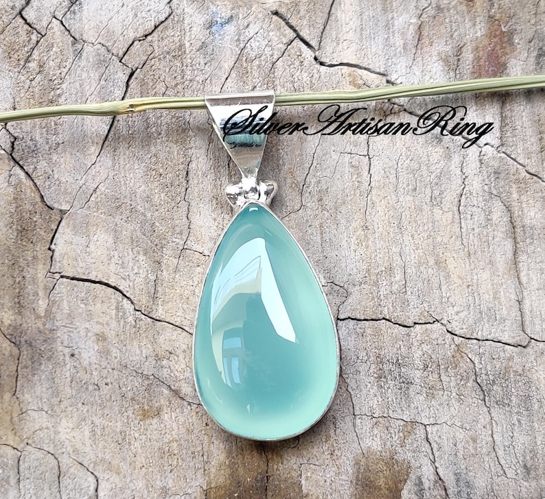 May include: A teardrop-shaped pendant featuring a light blue chalcedony gemstone set in sterling silver.