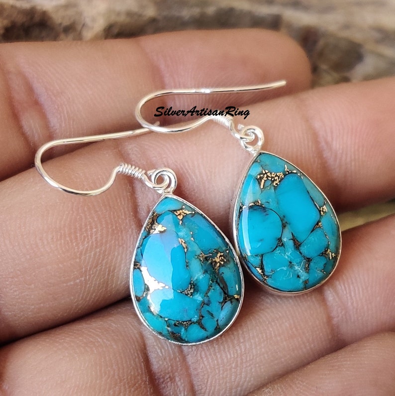 Pu&ograve; includere: Orecchini a goccia turchese e oro con ganci d'argento. Gli orecchini sono in argento sterling e presentano una pietra turchese naturale con accenti dorati.
