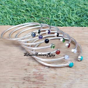 Pode incluir: Um conjunto de pulseiras de prata com pedras preciosas de diferentes cores. As pulseiras est&atilde;o empilhadas umas sobre as outras e as pedras preciosas s&atilde;o vis&iacute;veis. As pedras preciosas s&atilde;o turquesa, branca, vermelha, verde, preta, roxa e azul.