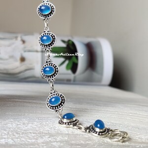 May include: A silver bracelet with blue gemstone accents. The bracelet has a lobster claw clasp.