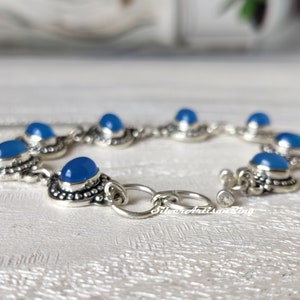 May include: A silver bracelet with blue gemstone accents. The bracelet has a toggle clasp and is made of sterling silver.