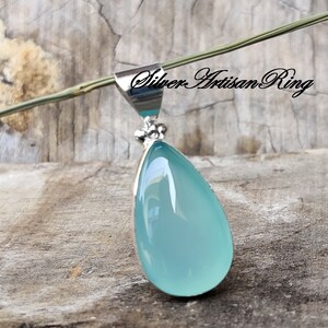 May include: A teardrop-shaped pendant featuring a light blue chalcedony gemstone set in sterling silver.