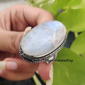 May include: A silver ring with a large oval moonstone. The ring has a detailed silver band.