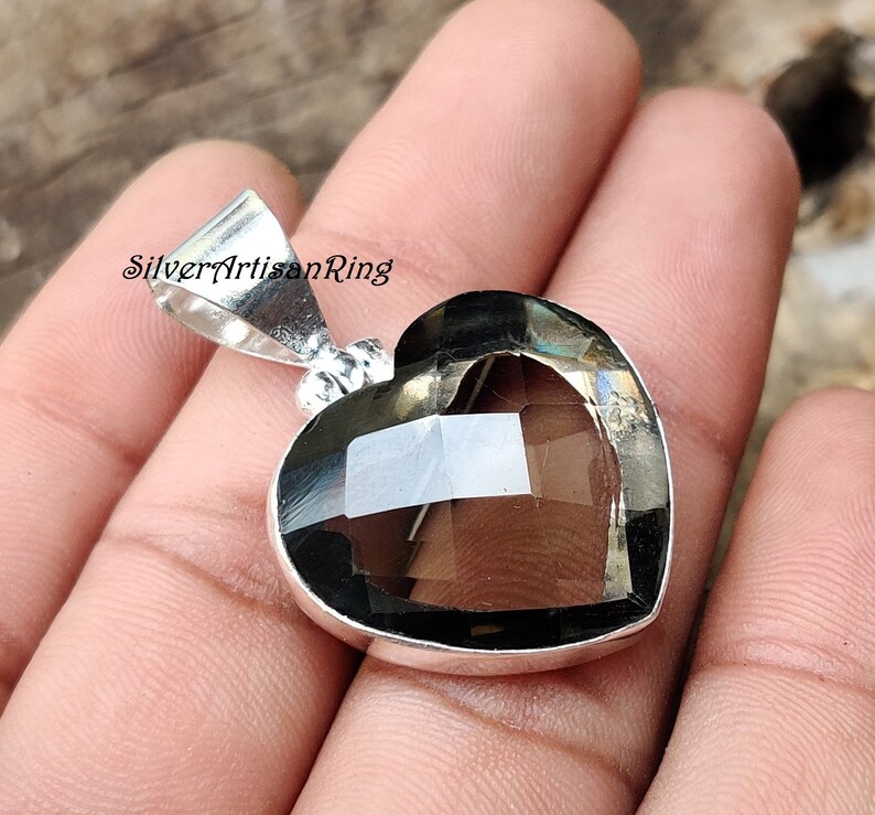 May include: A silver heart-shaped pendant with a smoky quartz gemstone. The pendant is on a silver chain.