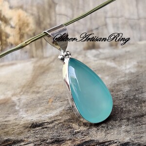 May include: A teardrop-shaped pendant featuring a light blue chalcedony stone set in sterling silver. The pendant has a bail for attaching to a chain.