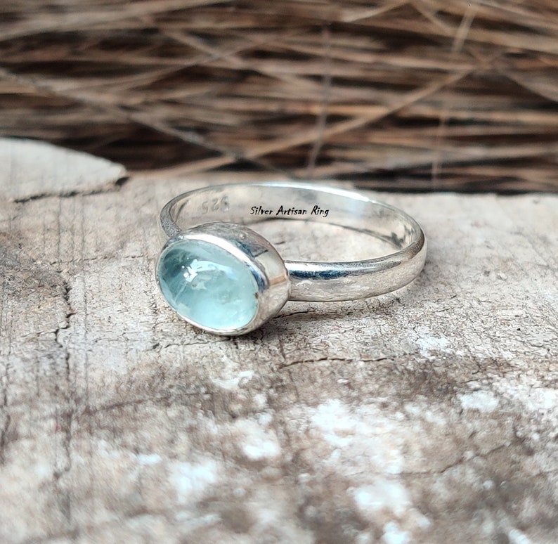 Puede incluir: Un anillo de plata con una piedra ovalada azul claro. El anillo est&aacute; marcado con "Silver Artisan Ring".