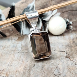 Pode incluir: Um pingente de prata com uma pedra preciosa de quartzo fumado marrom. O pingente tem formato retangular e um acabamento liso e polido. A pedra preciosa est&aacute; engastada em um bezel de prata e tem uma apar&ecirc;ncia ligeiramente nublada.