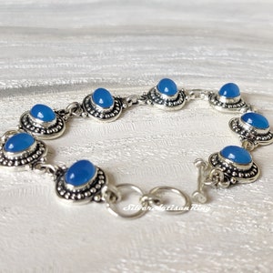 May include: A silver bracelet with blue chalcedony gemstones. The bracelet has a toggle clasp.
