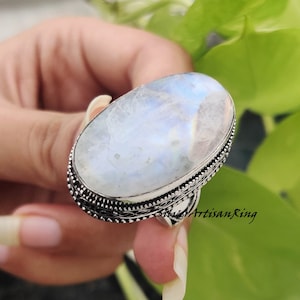 May include: A silver ring with a large oval moonstone. The ring has a detailed silver band.