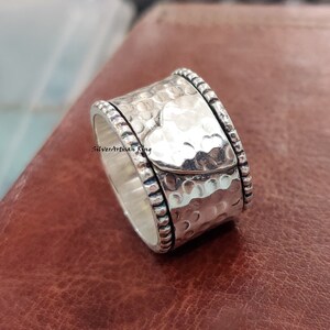 Pu&ograve; includere: Un anello girevole in argento con finitura martellata e un design a forma di cuore. L'anello ha un bordo perlato.