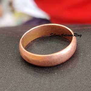 Op de afbeelding: Een eenvoudige koperen bandring met een gladde, licht getextureerde afwerking.