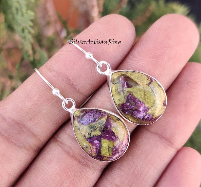 Pu&ograve; includere: Un paio di orecchini pendenti in argento con gocce di pietre preziose verdi e viola. Gli orecchini hanno una forma a goccia e sono realizzati in argento sterling.