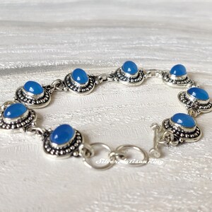 May include: A silver bracelet with blue chalcedony gemstones. The bracelet has a toggle clasp.