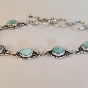 May include: A silver bracelet with a toggle clasp and oval-shaped turquoise stones.