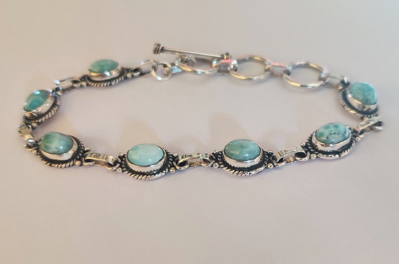 May include: A silver bracelet with a toggle clasp and oval-shaped turquoise stones.