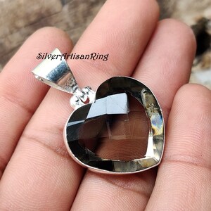 May include: A silver heart-shaped pendant with a smoky quartz gemstone. The pendant has a bail for attaching to a chain.