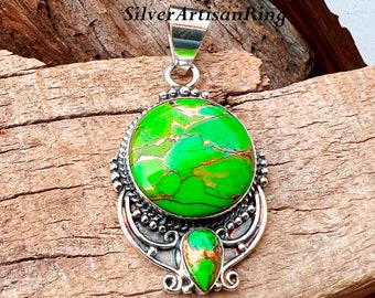 May include: A silver pendant with a green and gold turquoise stone. The pendant has a detailed design with a smaller teardrop-shaped stone at the bottom.