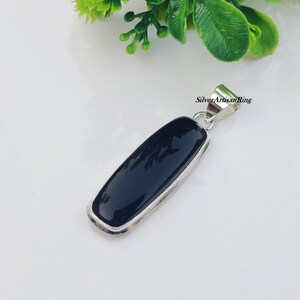 May include: A black onyx pendant with a silver bail. The pendant is rectangular in shape and has a smooth, polished finish.