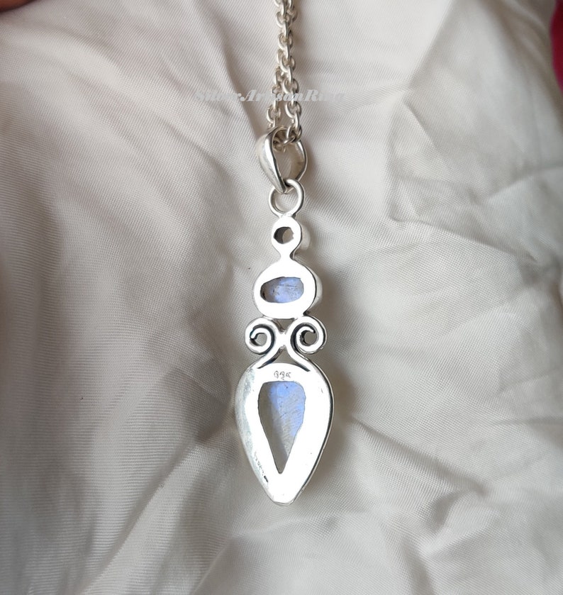 May include: Silver pendant with a teardrop-shaped moonstone and a smaller oval moonstone. The pendant has a detailed design with swirls and the number 925 stamped on the back.