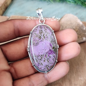 May include: A silver pendant with a large oval-shaped purple and green stone set in a silver bezel. The stone has a unique, swirling pattern.