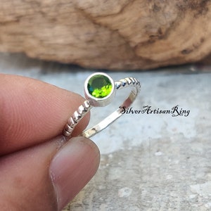 May include: A silver ring with a twisted band and a green gemstone. The text "Silver Artisan Ring" is visible in the background.