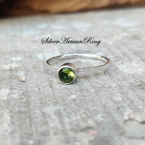 May include: A silver ring with a green gemstone. The ring is simple and elegant, and the gemstone is a beautiful shade of green.