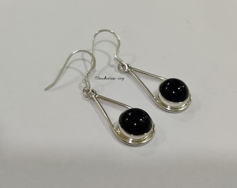 May include: A pair of silver dangle earrings with black round gemstones. The earrings have a triangular shape and a hook closure.